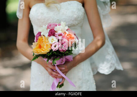 Bride Holding Wedding Bouquet with Orange white and Pink Flowers Stock Photo