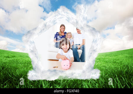 Composite image of cheerful little boy inserting coin in a piggybank Stock Photo