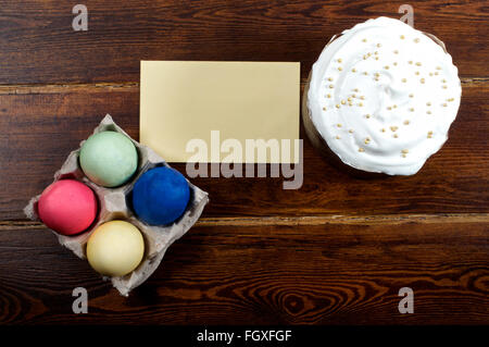 Easter cake with different eggs and card over wooden background from top Stock Photo