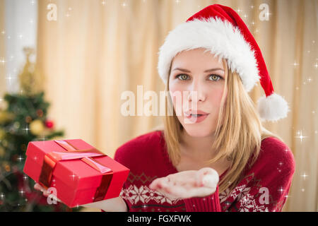 Composite image of pretty blonde in winter fashion blowing over hands Stock Photo