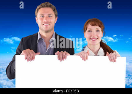 Composite image of smiling couple holding large sign Stock Photo