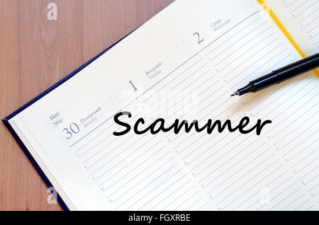 Scammer text concept write on notebook with pen Stock Photo