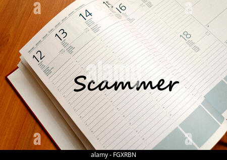 Scammer text concept write on notebook with pen Stock Photo