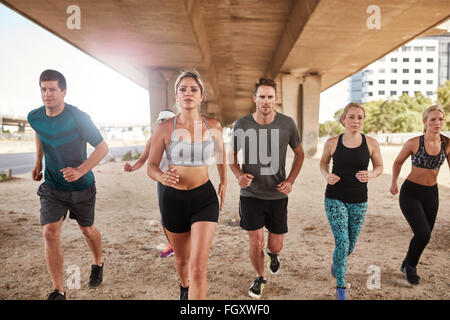 Determined group of athletes running. Runners in sportswear training together in the city. Stock Photo