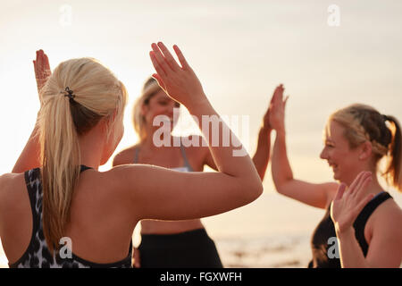 Runners giving high five to each other after a good training session. Group of athletes celebrating success. Stock Photo