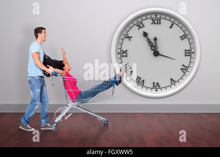 Composite image of young couple having fun with shopping cart Stock Photo