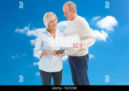 Composite image of mature couple working out their bills Stock Photo