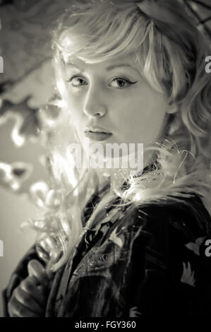 Black and white picture of a young lady wearing a silk kimono and holding an umbrella Stock Photo