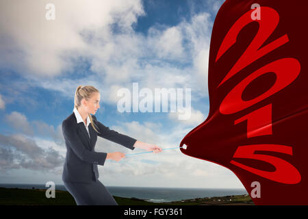 Composite image of focused blonde businesswoman pulling a rope Stock Photo