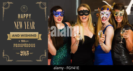 Composite image of laughing friends wearing masks holding champagne glasses Stock Photo