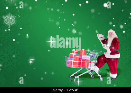 Composite image of santa pushes a shopping cart while reading Stock Photo
