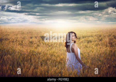 Beautiful woman in a corn field with dramatic sky . Sunset light Beautiful woman in a corn field with dramatic sky . Sunset light