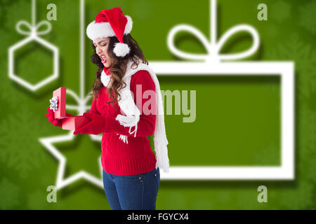 Composite image of disgusted brunette opening christmas gift Stock Photo