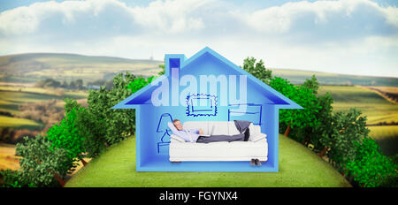 Composite image of portrait of smiling businessman with laptop lying on sofa Stock Photo