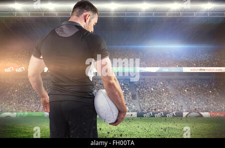 Composite image of tough rugby player holding ball Stock Photo