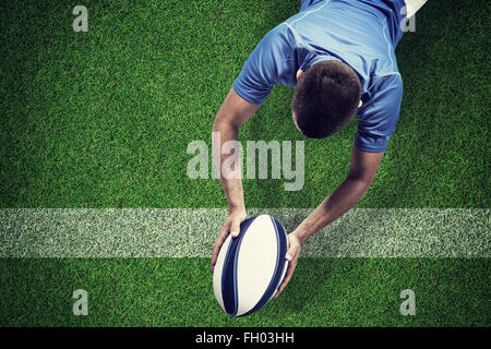 Composite image of rugby player lying in front with ball Stock Photo
