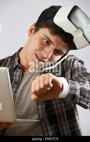 Man In Virtual Reality Headset Looking At Smart Watch And Talking On Mobile Phone Stock Photo