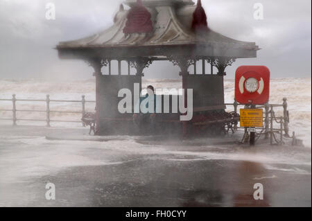 Storm on the old  Blackpool south central shore sea front.  Male sheltering in a pagoda type shelter Stock Photo