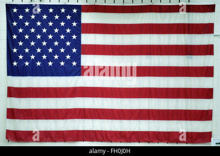 A large American flag on display on a wall in an Illinois high school gymnasium. Bartlett, Illinois, USA. Stock Photo