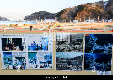 Newspapers show the damages after the 2011 Great East Japan Earthquake and Tsunami have stuck Onagawa city, while construction trucks continue working five years after, on February 11, 2016, Miyagi Prefecture, Japan.  A few weeks before of the fifth anniversary of 2011 Tohoku Earthquake and Tsunami, the Japanese government announced that the second half of the reconstruction work in the Tohoku area is expected to be concluded before the 2020 Tokyo Olympics begin. According to the official Reconstruction Agency's website approximately $250 billion were allocated to the first period (2011-2015)  Stock Photo