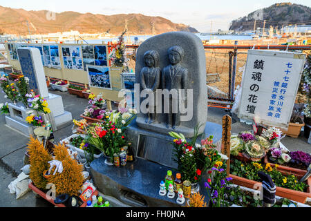 Floral tribute for the victims of the 2011 Great East Japan Earthquake and Tsunami have stuck Onagawa city, while construction trucks continue working five years after, on February 11, 2016, Miyagi Prefecture, Japan.  A few weeks before of the fifth anniversary of 2011 Tohoku Earthquake and Tsunami, the Japanese government announced that the second half of the reconstruction work in the Tohoku area is expected to be concluded before the 2020 Tokyo Olympics begin. According to the official Reconstruction Agency's website approximately $250 billion were allocated to the first period (2011-2015)  Stock Photo