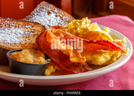 A delicious breakfast platter with thick-cut applewood smoked bacon, scrambled eggs, french toast and apple puree Stock Photo