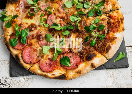 Pizza salami and ham with cheese and cornsalad leaves , rustic fresh baked italian pizza Stock Photo