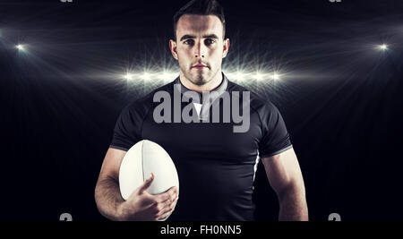 Composite image of tough rugby player holding ball Stock Photo