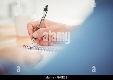 Man writing on spiral table at desk Stock Photo