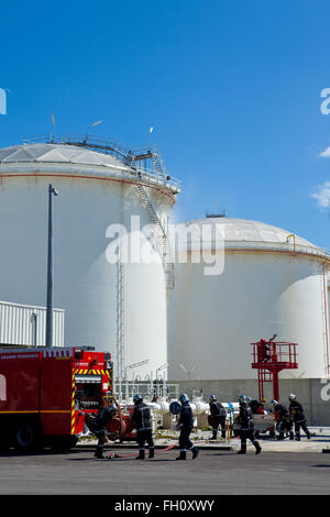 Firefighters applying foam to oil storage tank Stock Photo