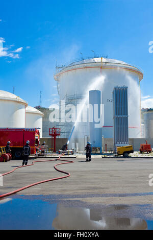 Firefighters applying foam to oil storage tank Stock Photo