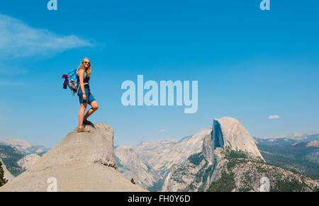 Hiker standing on a cliff, behind Half Dome, view from Glacier Point, Yosemite National Park, California, USA Stock Photo
