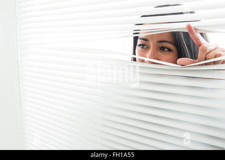 Woman peeking through some window blinds Stock Photo