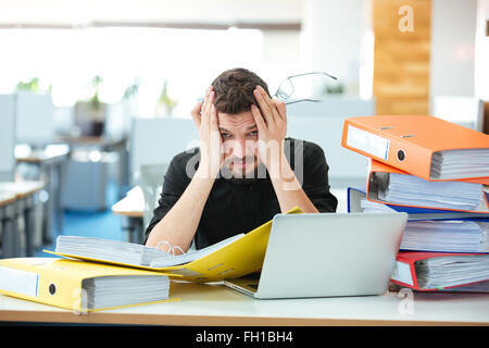 Tired businessman working with papers in office Stock Photo