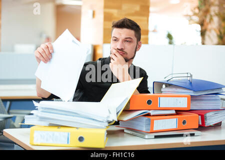 Businessman sitting at the table and reading documents in office Stock Photo