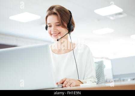 Happy woman working on laptop computer in call center Stock Photo