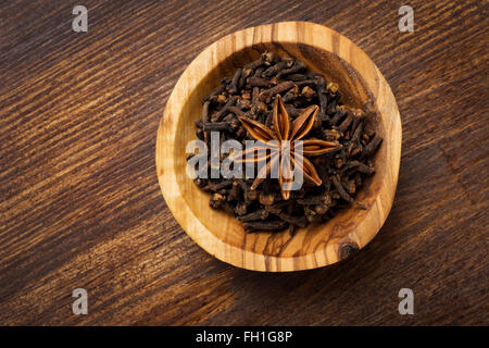Small bowl with Cloves and anise star on vintage wooden background Stock Photo
