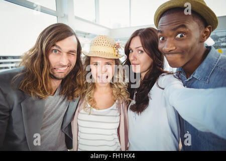 Woman taking selfie with coworkers making faces Stock Photo