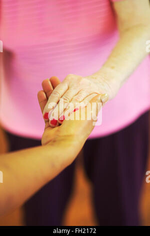 social care at a UK nursing home, as a female health worker holds the hand of an elderly dementia sufferer Stock Photo