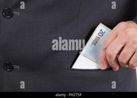 Man in suit putting a wad of twenty Euros banknotes in his pocket. Stock Photo