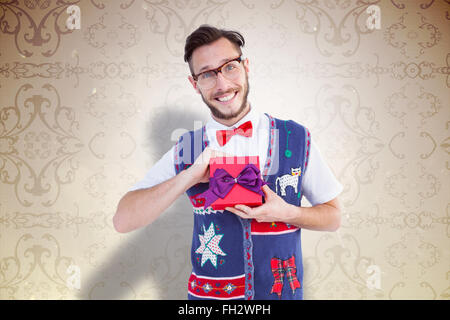 Composite image of geeky hipster offering christmas gift Stock Photo