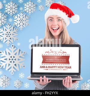 Composite image of festive blonde holding a laptop Stock Photo