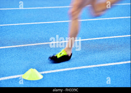 Blurred athlete by a slow camera shutter speed competing on blue sprint track Stock Photo