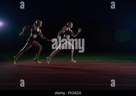 athletic runners passing baton in relay race Stock Photo