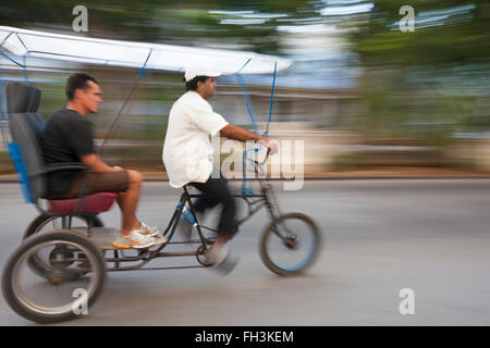 Daily life in Cuba - bicitaxi bicycle taxi speeding along the road at the El Malecon, Havana, Cuba, West Indies, Caribbean, Central America Stock Photo