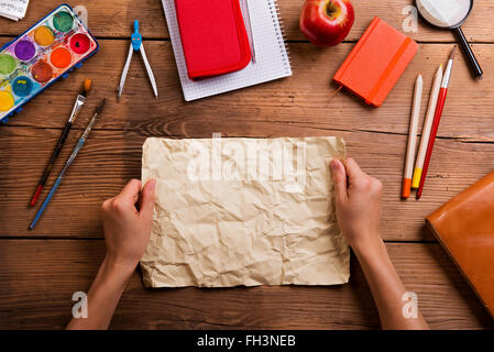 Hands of man with rumpled paper. Various school supplies. Stock Photo