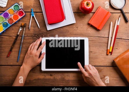 Hands of man with tablet. Various school supplies. Stock Photo
