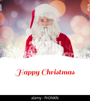 Composite image of santa holding his sack and keeping a secret Stock Photo