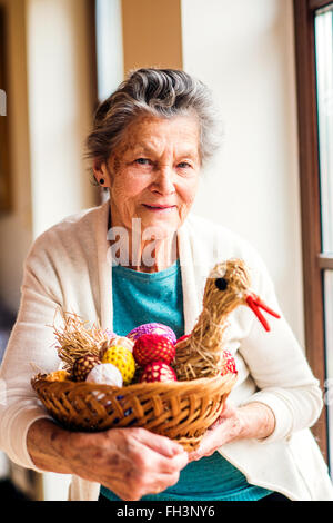Woman holding basket with Easter eggs and straw hen Stock Photo