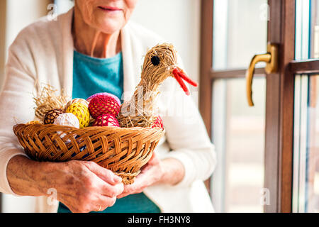 Woman holding basket with Easter eggs and straw hen Stock Photo